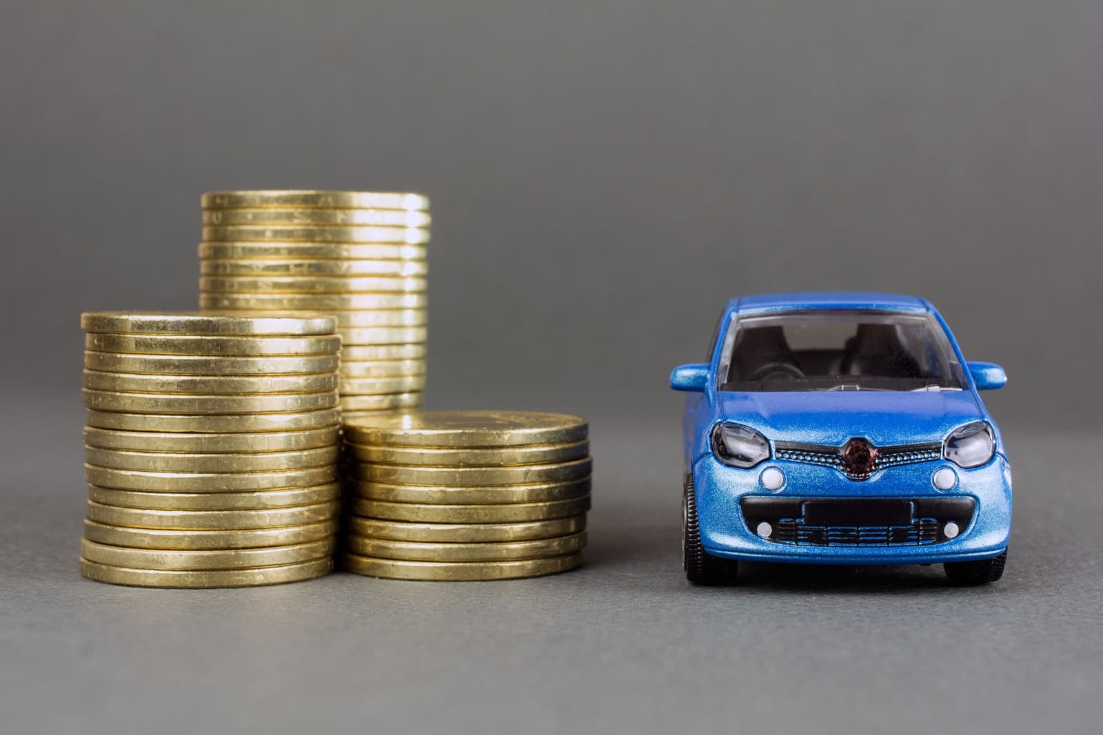Blue toy car next to stack of pound coins, representing cost of servicing