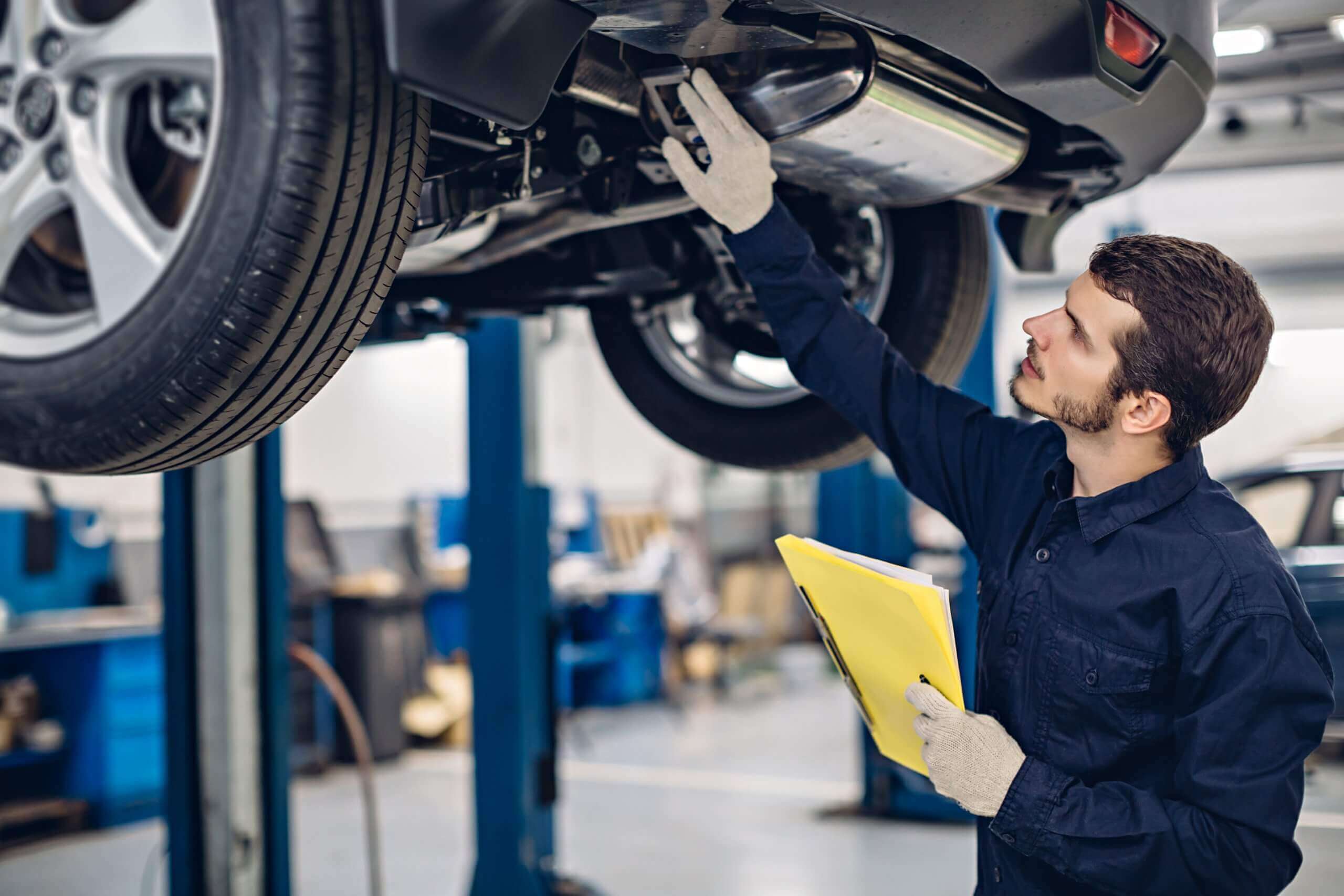 Mechanic holding a clipboard completing an MOT inspection