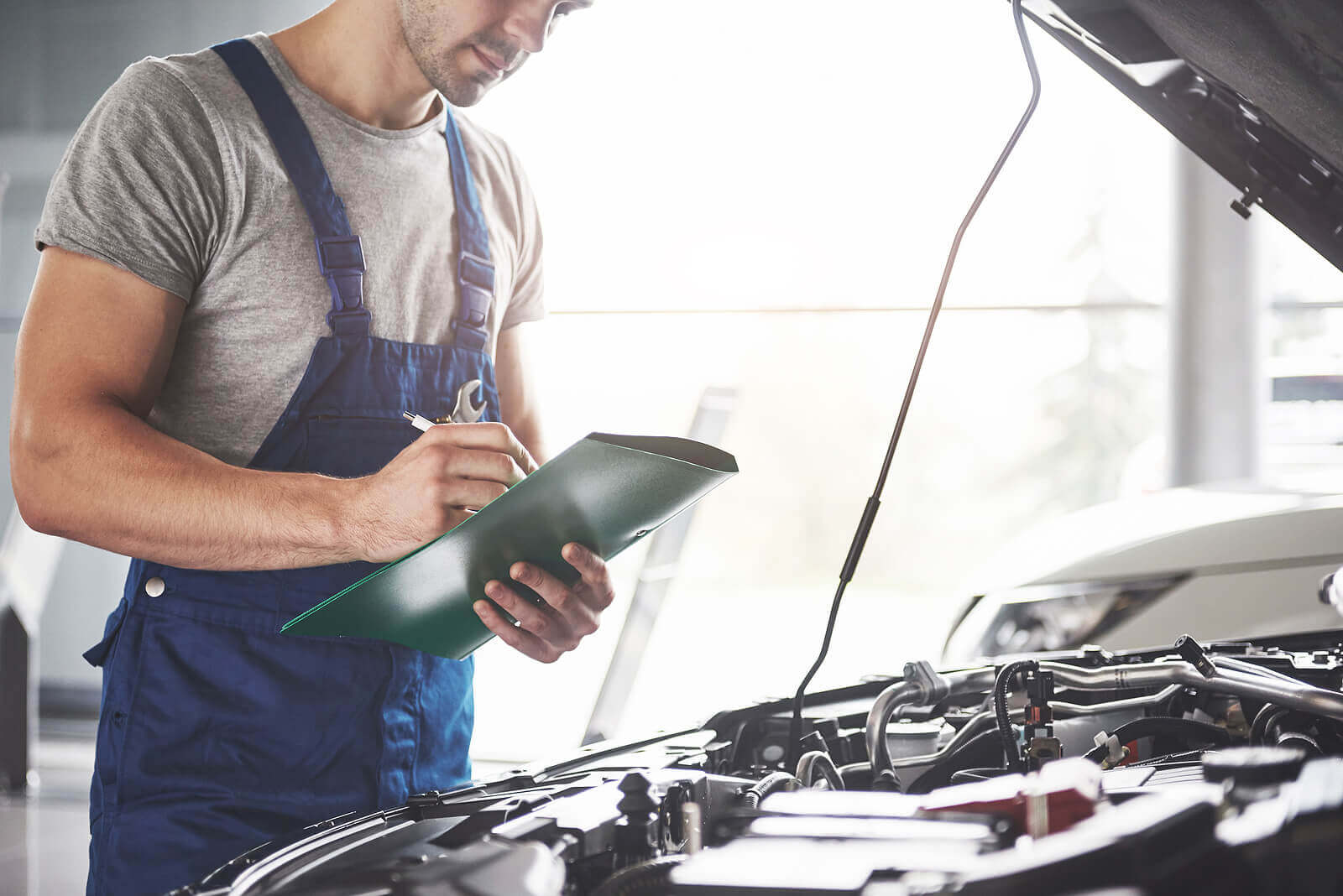 Mechanic in dungarees inspecting car during an MOT retest